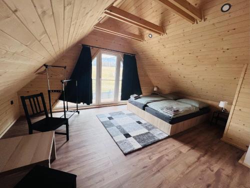 an attic room with a bed and a ladder and a window at Rezortík Gerlachov CHATA 2 in Gerlachov