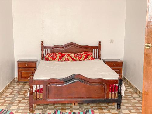 1 dormitorio con cama de madera y almohadas rojas en وكالة أمتار لكراء المنازل 