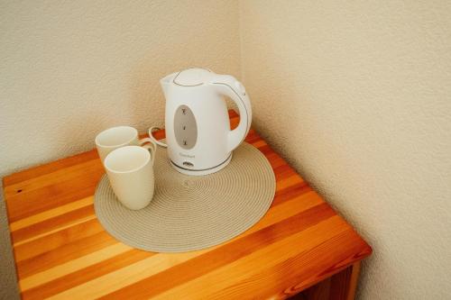 - Cafetera y 2 tazas en una mesa de madera en Beach Bus Hotel en Roja