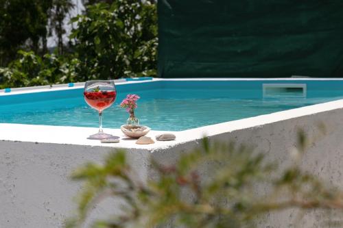 a glass of wine sitting on a ledge next to a swimming pool at Casa Trilhos da Serra in Alcobertas