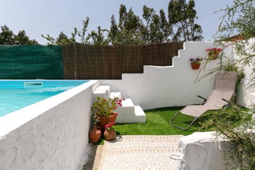 a backyard with a swimming pool and a white wall at Casa Trilhos da Serra in Alcobertas