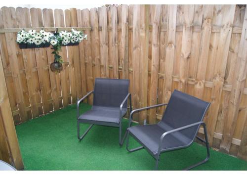 two chairs sitting in front of a wooden fence at Ferienwohnungen TalBach in Simmerath