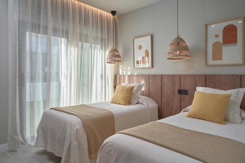two beds in a room with a window at Salobre Oasis Suites in Salobre