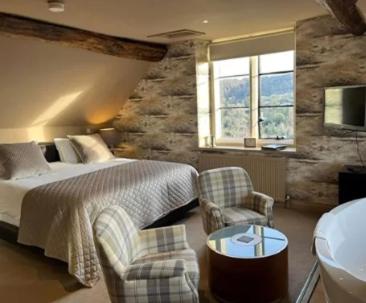 a hotel room with a bed and chairs and a television at Bagshaw Hall in Bakewell