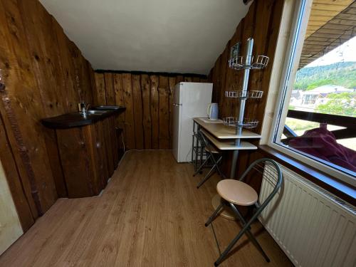 a small kitchen with a table and a refrigerator at Приват-котедж Зарінок in Mykulychyn