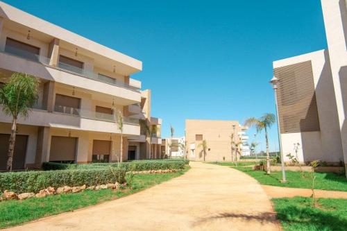 een loopbrug voor een gebouw met palmbomen bij Superbe appartement luxueux idéalement situé à la marina saidia in Saidia 