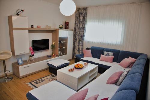 a living room with a blue couch and pink pillows at Apartman Flumen in Mostar