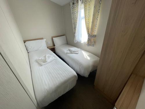 2 Betten in einem kleinen Zimmer mit Fenster in der Unterkunft Marine Holiday Park D & S rental A in Rhyl