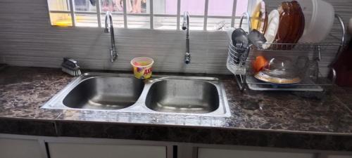 - un comptoir de cuisine avec évier en acier inoxydable dans l'établissement BB Bahau Homestay, à Bahau