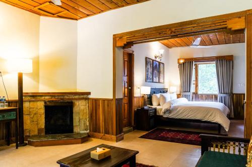 a bedroom with a bed and a fireplace at Greens By Roomy, Kalam in Kalām