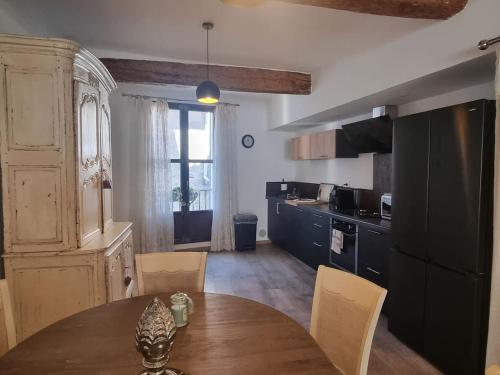a kitchen with a wooden table and a dining room at L isle aux rêves Nid douillet au cœur de ville in L'Isle-sur-la-Sorgue