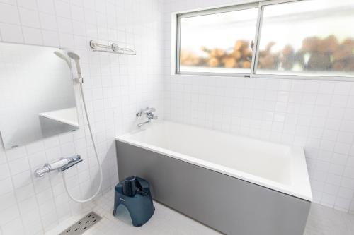 a white bathroom with a tub and a window at 南伊豆　貸別荘　夜空の星 in Minamiizu