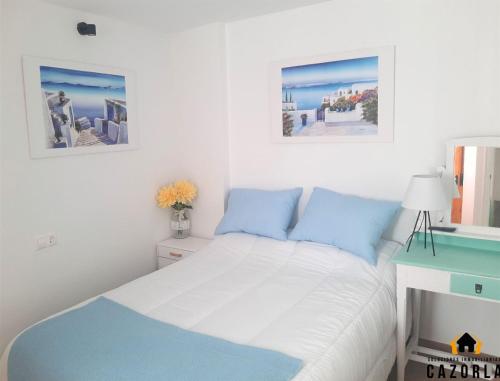 a bed in a bedroom with two pictures on the wall at CASA CARMELA in Cazorla