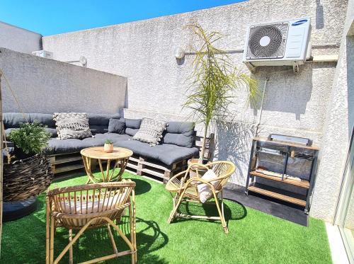 a patio with a couch and chairs and a table at AppartCosy Emplacement Idéal avec Terrasse & Parking Privé in Nîmes