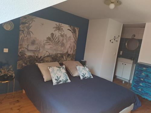 um quarto com uma cama azul com almofadas em Chambre d'hôte des Thermes em Vichy