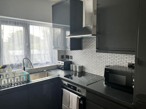 a kitchen with black cabinets and a sink and a microwave at The Crouch - Apartment 2 in Grays Thurrock