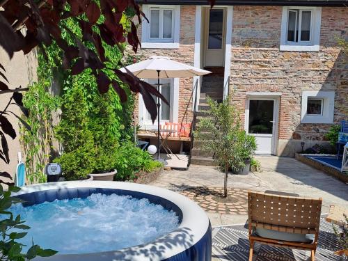 - un bain à remous dans une cour avec une chaise et un parasol dans l'établissement Chambre d'hôte des Thermes, à Vichy