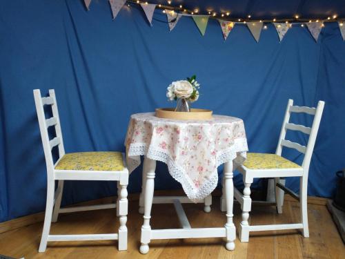 a table with two chairs and a table with flowers on it at South Wales Yurt-Cosy, log burner & private garden 