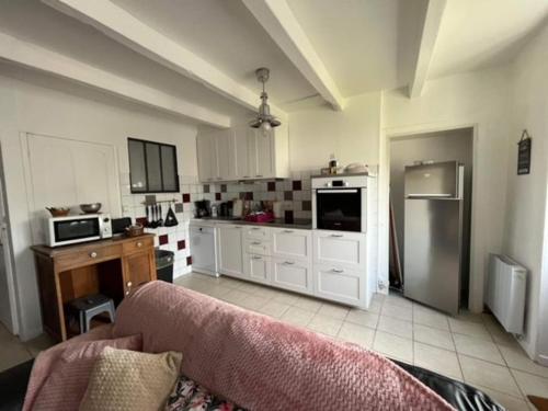 une grande cuisine avec des placards blancs et un canapé dans l'établissement Charmant gite, base idéale pour visiter la région, à Quettreville-sur-Sienne