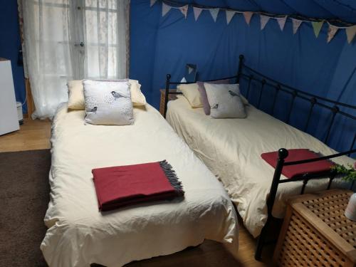two twin beds in a room with blue walls at South Wales Yurt-Cosy, log burner & private garden 