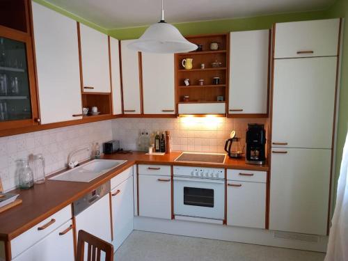 uma cozinha com armários brancos e um frigorífico branco em Ferienhaus em Maria Wörth