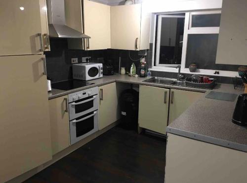 uma cozinha com um micro-ondas e um fogão forno superior em Double room Eastbourne em Polegate