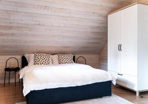 a bedroom with a bed and a wooden wall at Siedlisko Modrej Czapli. Domki na Kaszubach in Klonowo Dolne