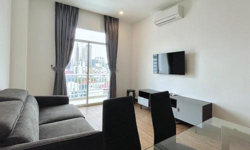 a living room with a couch and a tv and a window at Times Hotel at Bassac Lane in Phnom Penh