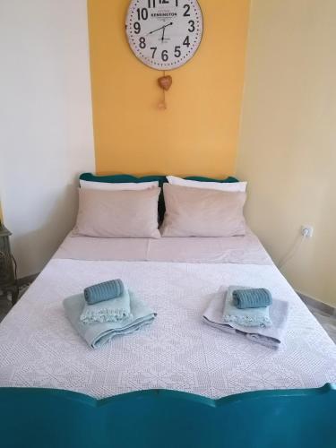 a bed with two towels on it with a clock on the wall at Vacation House in Agiokampos in AgiaKampos