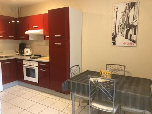 a kitchen with red cabinets and a table with chairs at Charmant studio situé à proximité des thermes 30 in Amélie-les-Bains-Palalda