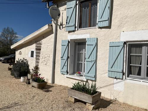 a house with blue shutters and plants in front of it at Le Jardin de Rose 24 FEUILLEBERT Romagne 86700 in Romagne