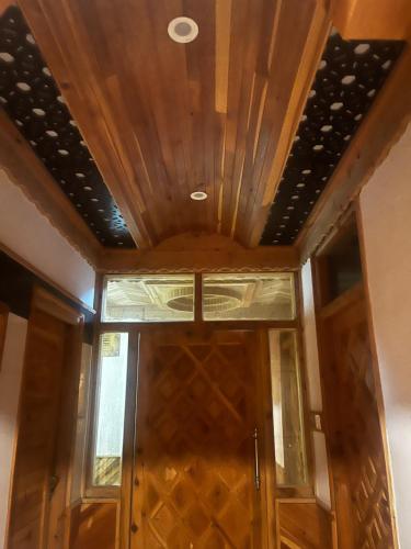 a room with a wooden ceiling and a glass door at Norvin Homes in Shimla
