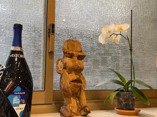 a bottle of wine next to a wooden figurine and a flower at Hotel Lukas Vegetarian & Vegan in Viareggio