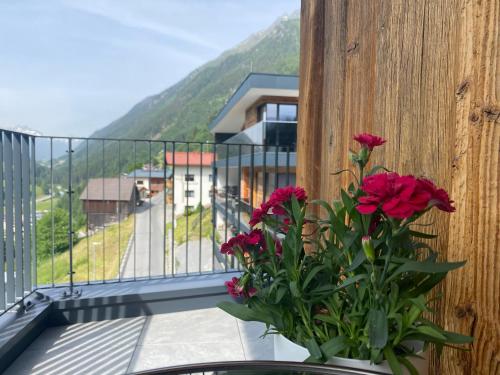 a vase of flowers on a balcony with a view at Hotel Apart Piz Mundin in Kappl
