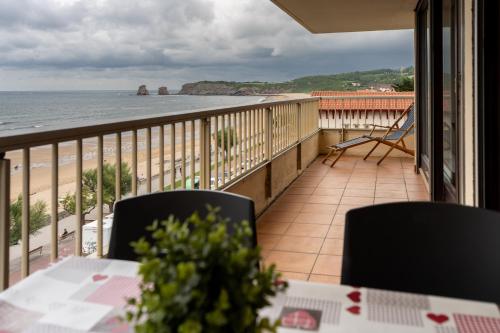 uma varanda com mesa e cadeiras e vista para a praia em Atlantic Selection - Vue panoramique sur l'océan avec Parking em Hendaye