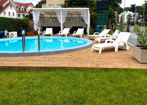 um deque com cadeiras, uma piscina e um monte de móveis em Wachta Rewal - grzany basen, bezpłatny parking em Rewal