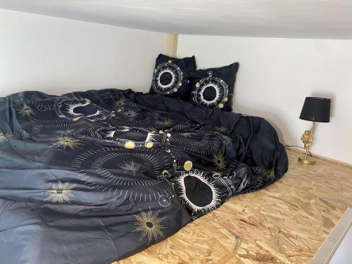 una cama con un edredón negro y dorado en La Domus Lemaitre 9 - Parking - TV - Wifi - Belgique, en Bavay