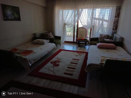 a room with two beds and a couch and a window at Rainfort apart Pınarkent 2+1 in Pamukkale