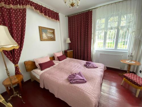 a bedroom with a bed with purple sheets and a window at Dworek nad Jeziorem Wądzyn in Bobrowo