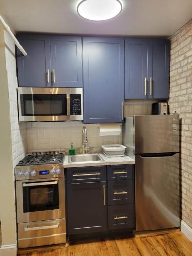 a kitchen with stainless steel appliances and blue cabinets at The Harlem Getaway in New York