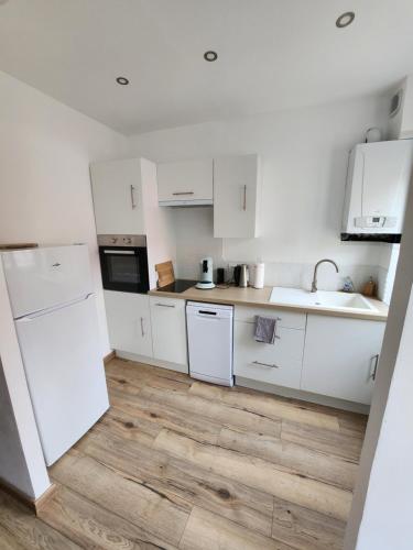 une cuisine avec des armoires blanches et un plancher en bois dans l'établissement Appartement proche des remparts, à Boulogne-sur-Mer
