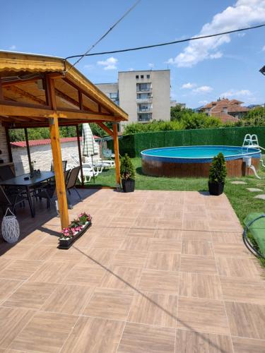eine Terrasse mit einem Tisch, einem Pavillon und einem Pool in der Unterkunft КЪЩА КАРБИ in Kardschali