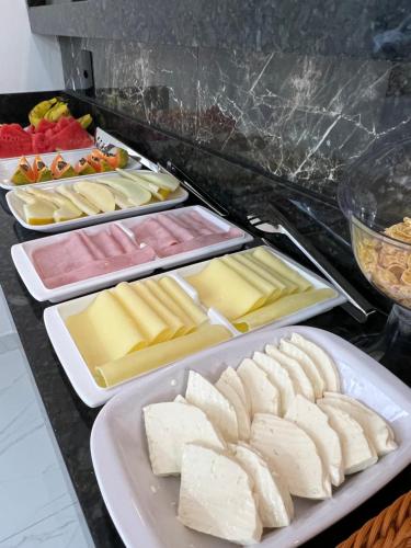 a buffet with several trays of cheese and other foods at Hotel Pousada Colliseu in Aparecida