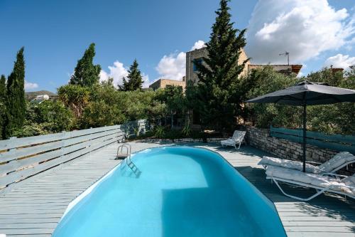 a blue swimming pool with an umbrella and chairs at Rogalida in Lambiní
