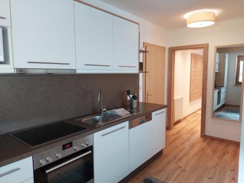 a kitchen with white cabinets and a sink at Haus Rene in Längenfeld