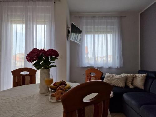 - un salon avec une table fleurie et un canapé dans l'établissement Apartments Marija, à Biograd na Moru