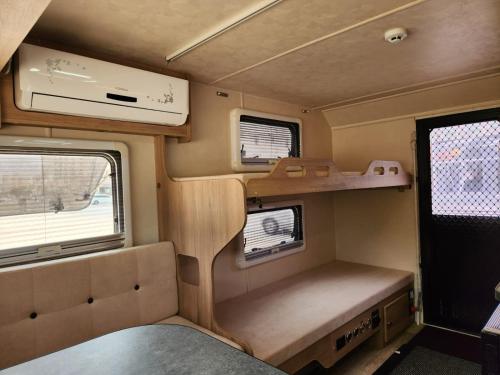 an interior of an rv with a bed and windows at Muscat Caravans in Barka