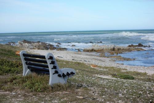 a bench sitting on the beach near the ocean at The Sun Catcher Bed & Breakfast in Struisbaai