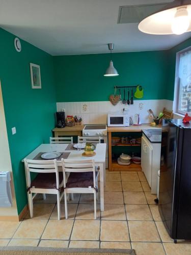 une cuisine avec des murs verts et une table et des chaises dans l'établissement l antre pot, à Arques-la-Bataille