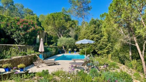 une piscine dans un jardin avec des chaises et un parasol dans l'établissement Azur Blue Villa; Rural Peace with private pool, à Peymeinade